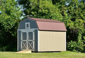 A light green and light red shed in the grass of an El Paso property.
