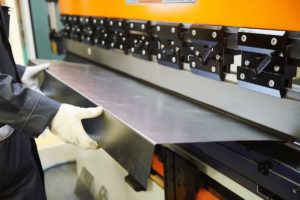 A person fabricating sheet metal using a machine in El Paso.
